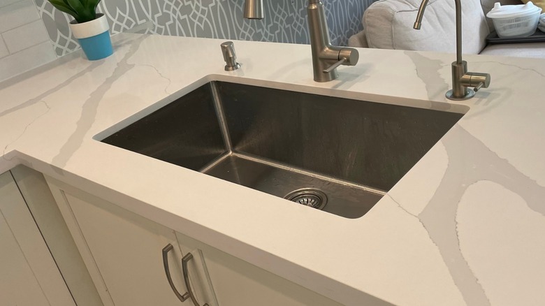Quartz countertop with a single stainless steel sink.
