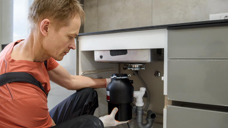 person fixing garbage disposal