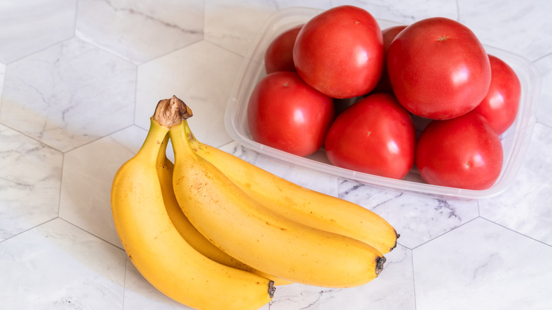 Tomatoes and bananas next to each other on a counter