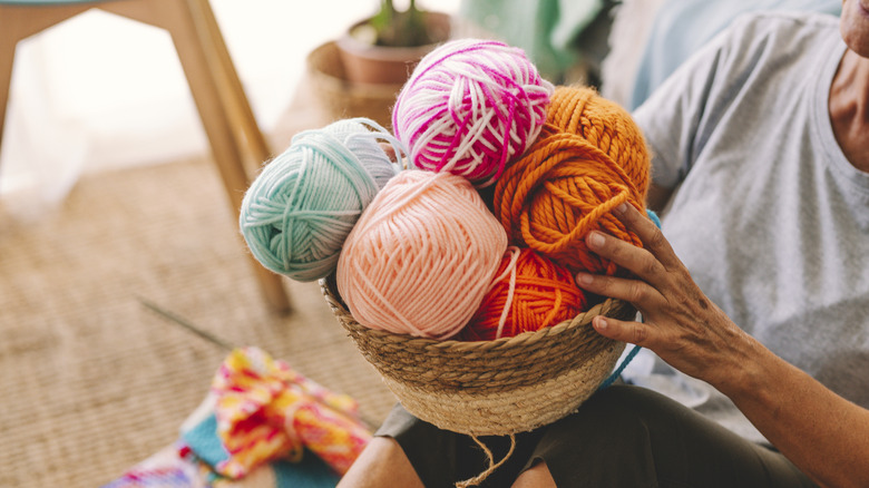 Person holding a basket of colorful yarn.
