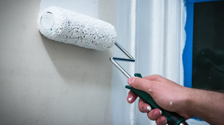 Person painting wall with roller