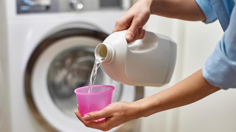 Close up of person pouring bleach into bottle cap
