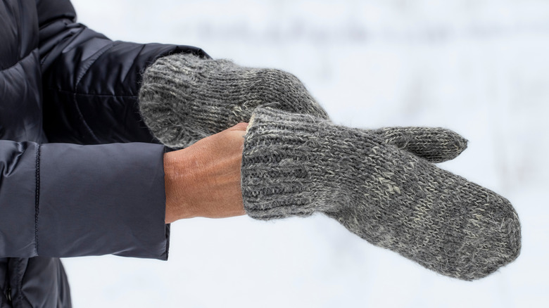 Person slips on a pair of gray mittens after washing them for the season.