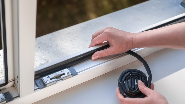 Weather stripping a window.