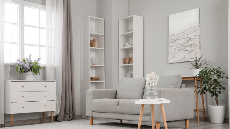 White shelves holding decor behind a gray couch