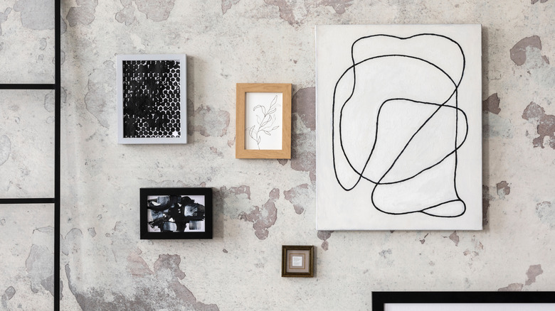 Gallery wall with paintings and photos in frames on concrete wall