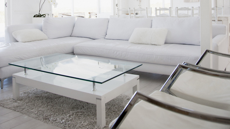 White double-tiered glass and wood table in a living room with white couches