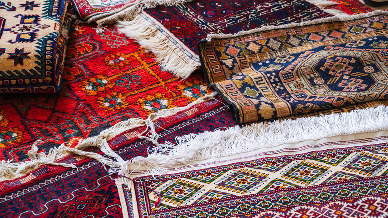 Assortment of colorful patterned rugs with fringes piled on the floor