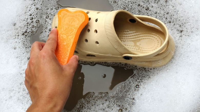 Person washing plastic shoes in soapy water