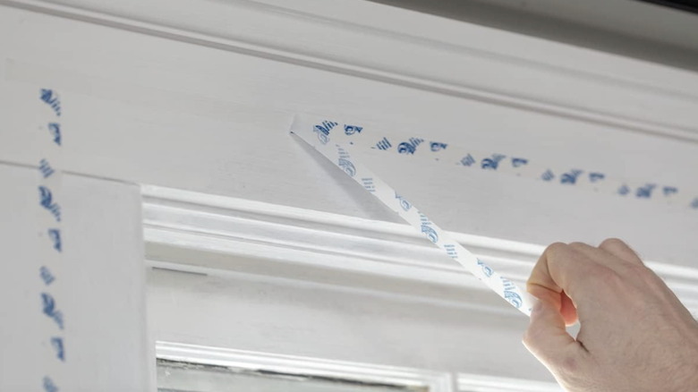 A person peels the sticker off of the Duck window insulation during installation
