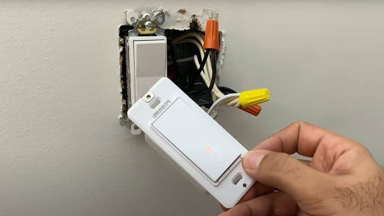 person installing a wireless light switch
