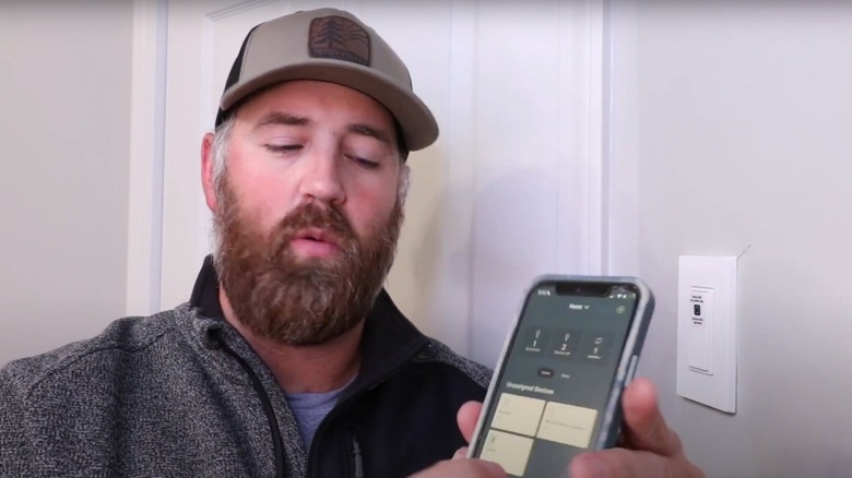 man changing wireless light switch with app