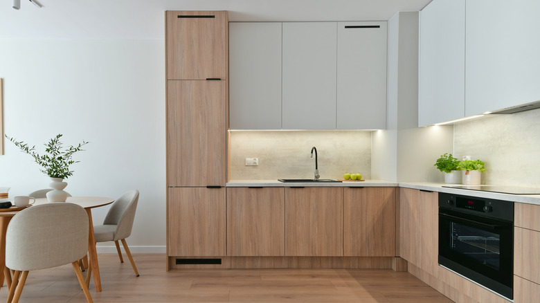 Compact minimalist built-in Scandinavian-style kitchen with appliances in oak and white with LED lights.