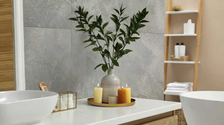 A small section of a bathroom showing a corner of the vanity and a tall shelf unit at the end of the bathtub
