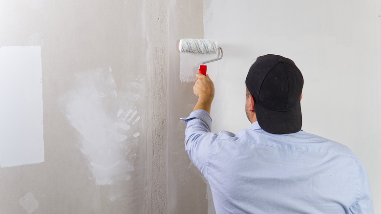 person painting drywall with roller