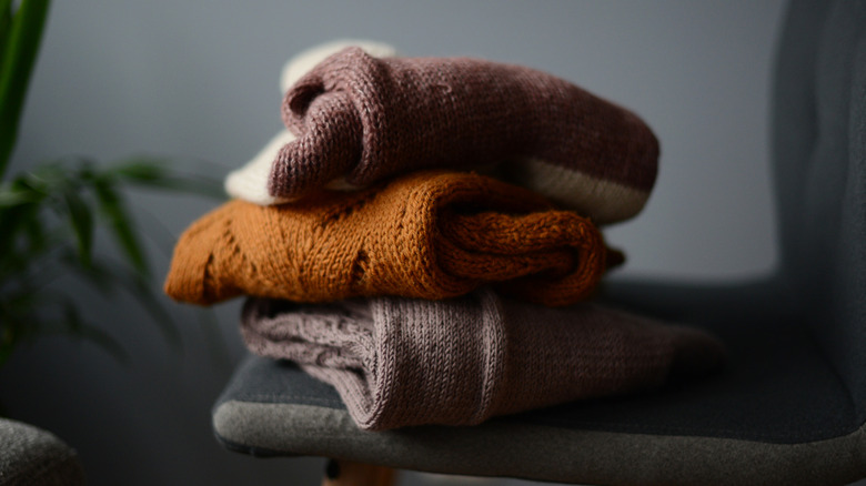 Three sweaters sitting on a chair