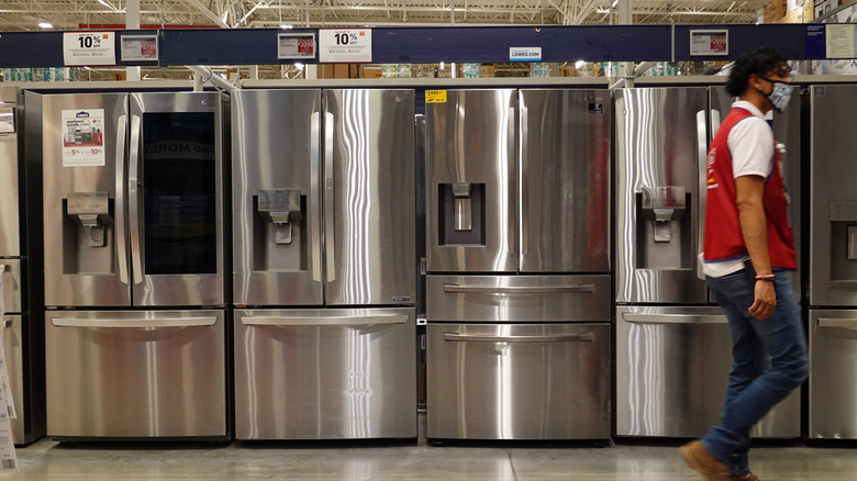 Lowe's worker walking past refrigerators