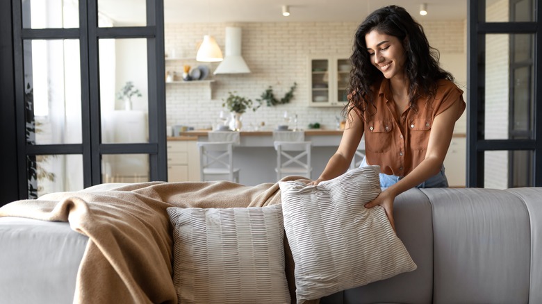 Woman putting cushion on sofa