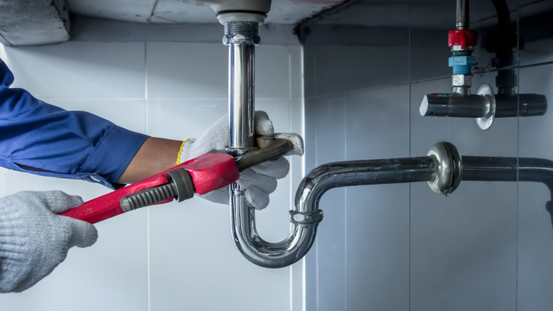 Person adjusting water pipe with a wrench