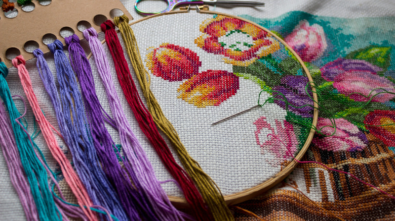 An embroidery hoop with flowers on it and and strings to make the design