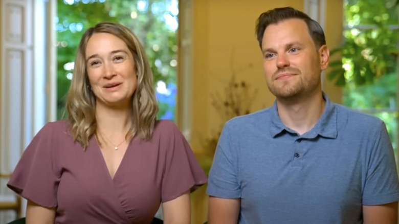 A couple on "House Hunters" sit next to each other on a sofa
