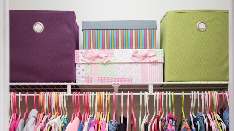 Various storage bins stacked on top closet shelf