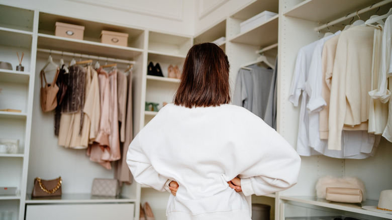 Woman in white sweatshirt looking at an organized closet