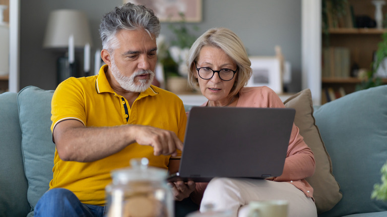 Older couple on the sofa consulting a laptop