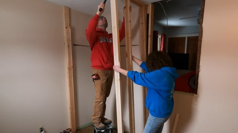 Two people securing framing for a closet wall