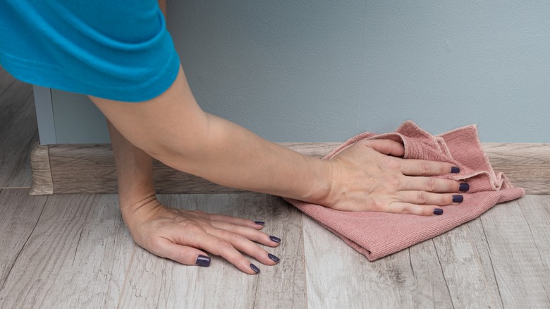 Person wiping baseboards with cloth