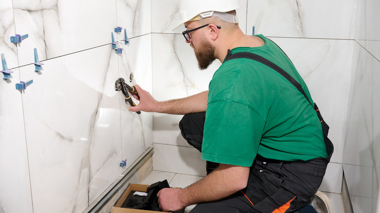 A man installs a handheld bidet sprayer in a bathroom