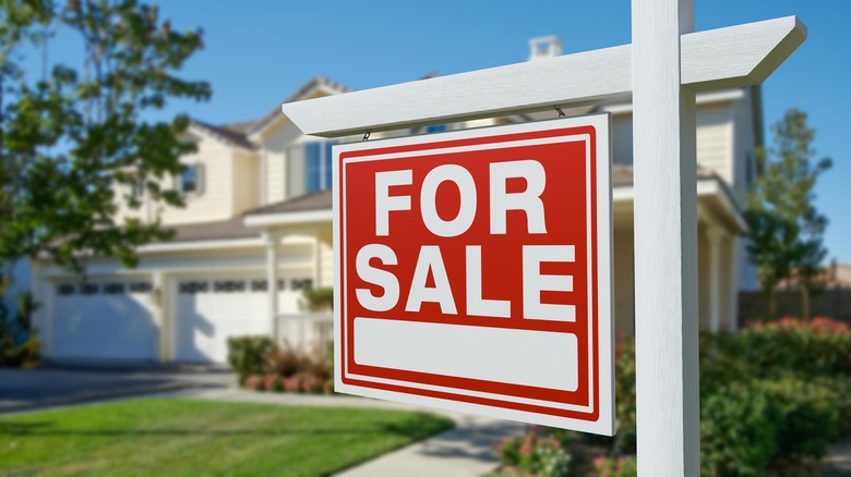 For Sale sign in front of white home