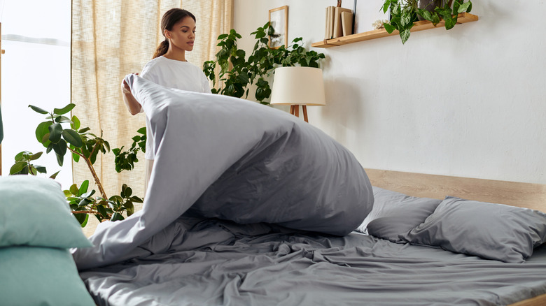 Woman removing duvet from bed to air it out