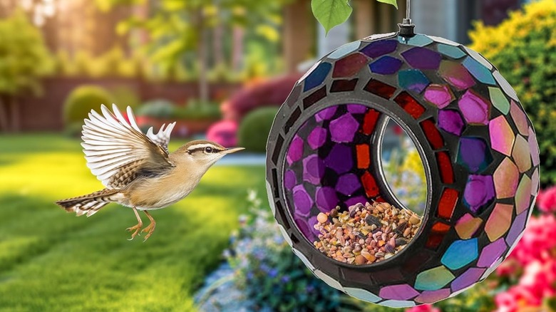 A glass mosaic bird feeder filled with bird seed