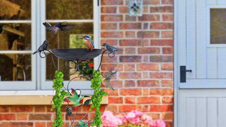 Metal birdbath decorated with climbing vine and metal birds.