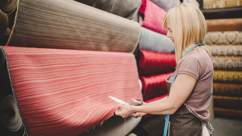 Woman measuring and cutting fabric.