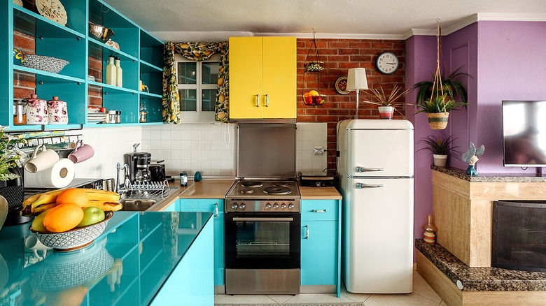 A kitchen featuring the colors aqua, yellow, purple, and white, plus brick