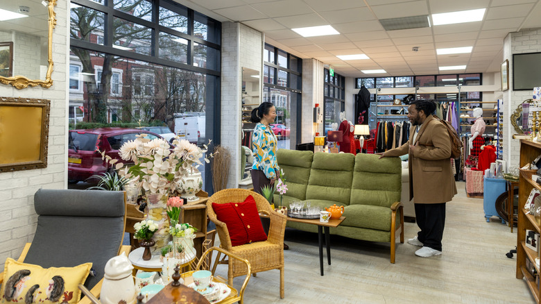 A man and woman look at vintage furniture in a secondhand shop.