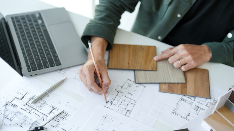 An interior designer sketching out a design project with wood swatches at a desk