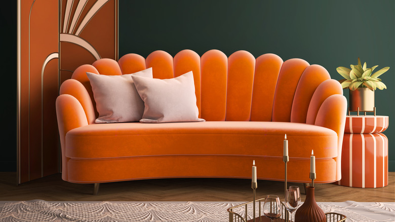 An orange Art Deco-style couch against an emerald green wall in a home
