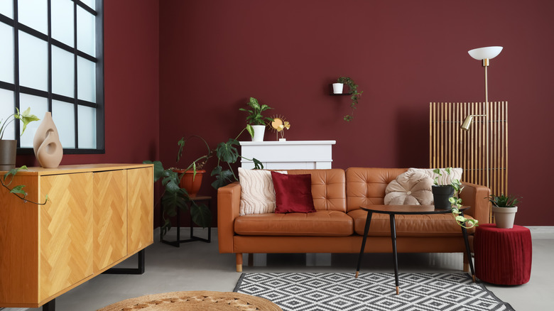 Living room with burgundy paint, muted orange couch and deep red accent side table.