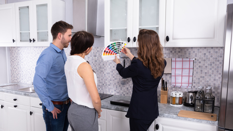 Woman showing color samples to young couple