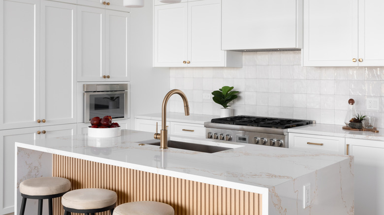 A white kitchen island with subtle gold veins in a waterfall design the top and sides