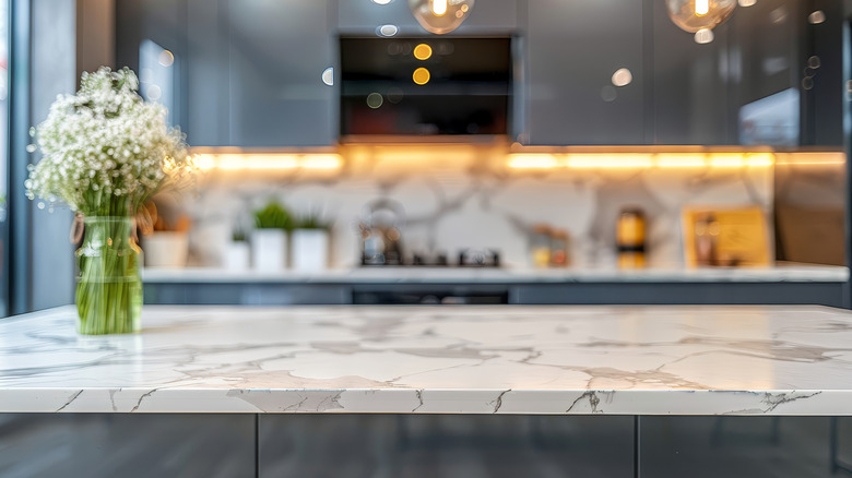 A heavily veined kitchen island with a clear vase and small white flowers