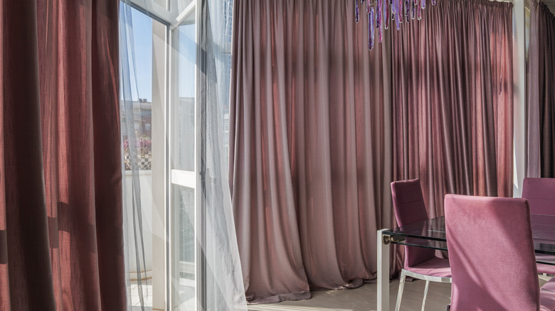 dusty rose pink drapes that pool onto the floor in an elegant room