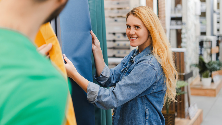 a woman picking out colorful drapes