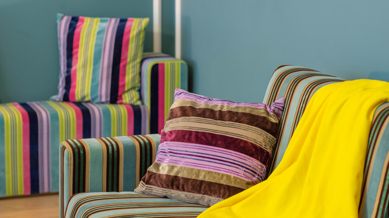 Two coloful, striped sofas against a pale green wall.