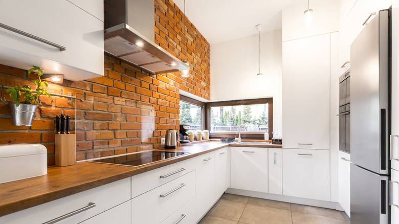 small kitchen with white cabinets and brick accent wall