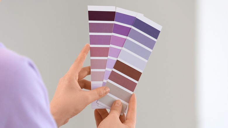 Hands holding up purple paint swatches