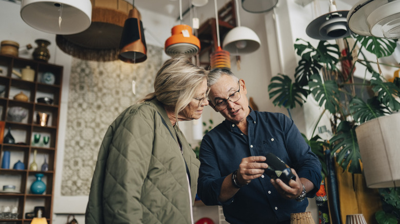 Two people in a shop looking at a glass vase